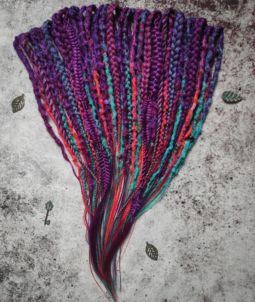 Synthetic dreads with purple transitioning into green and orange, complemented by braids